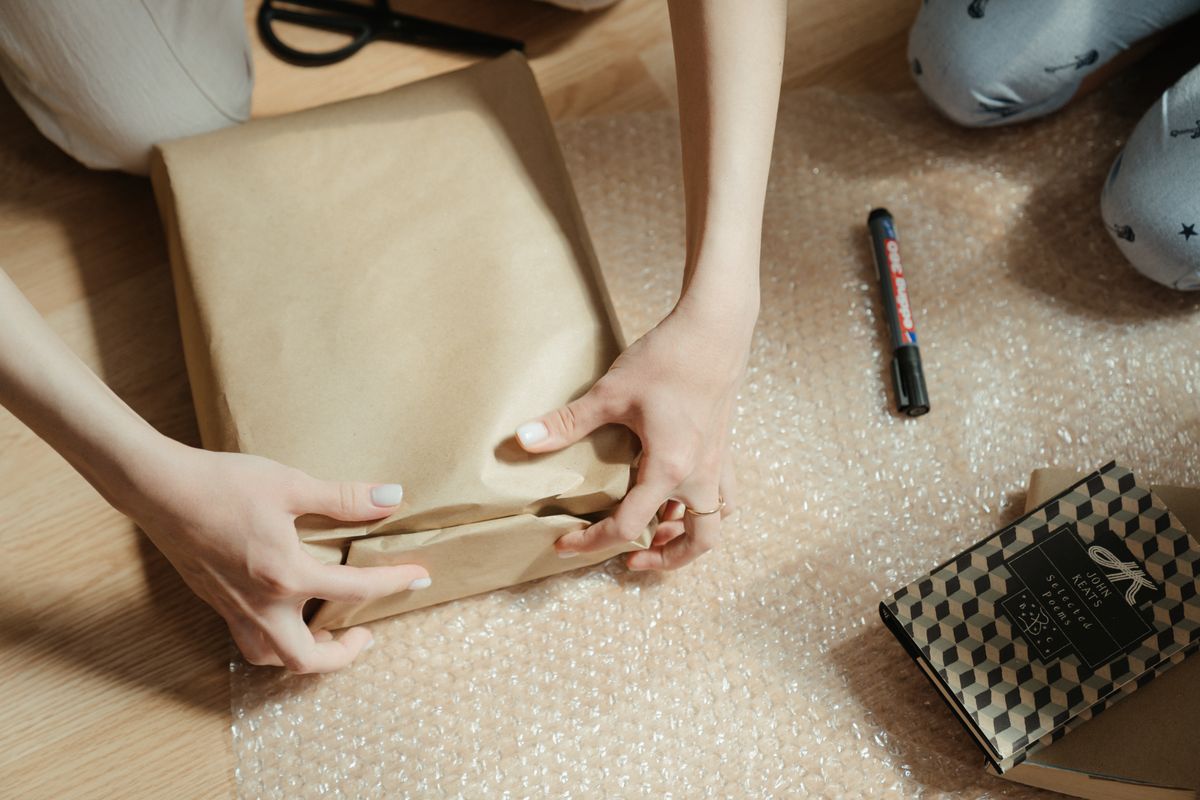 Hands wrapping a parcel in brown paper