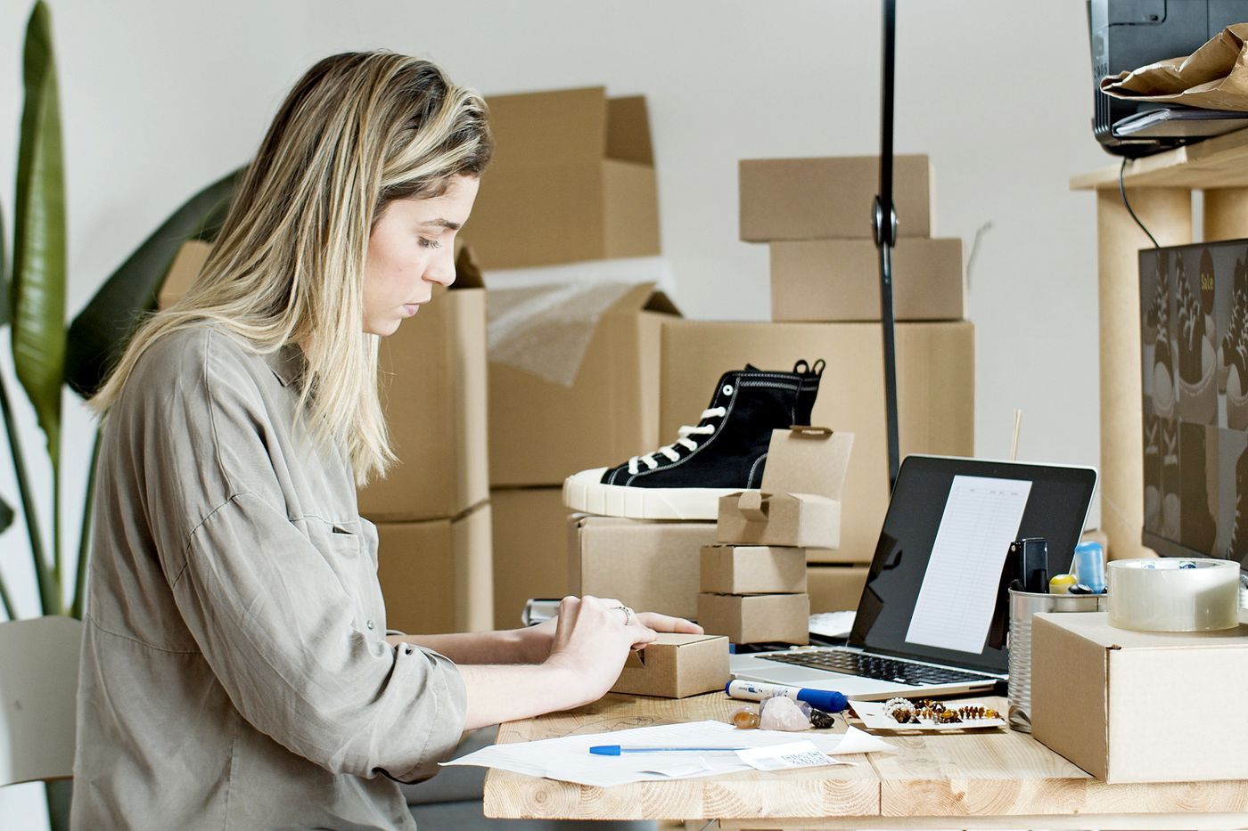 An online seller packing orders next to a laptop