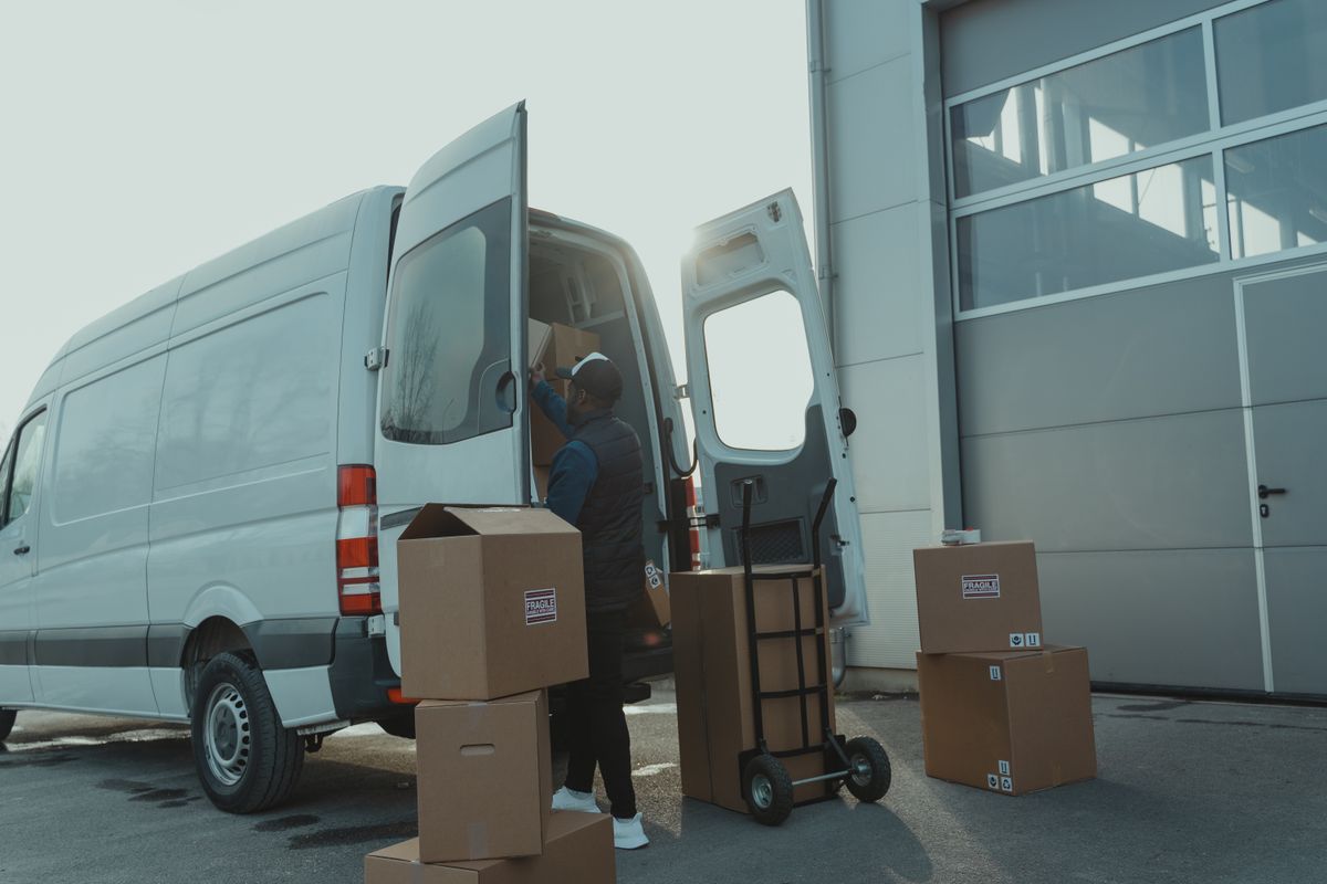 Parcels being loaded into a delivery van outside a warehouse